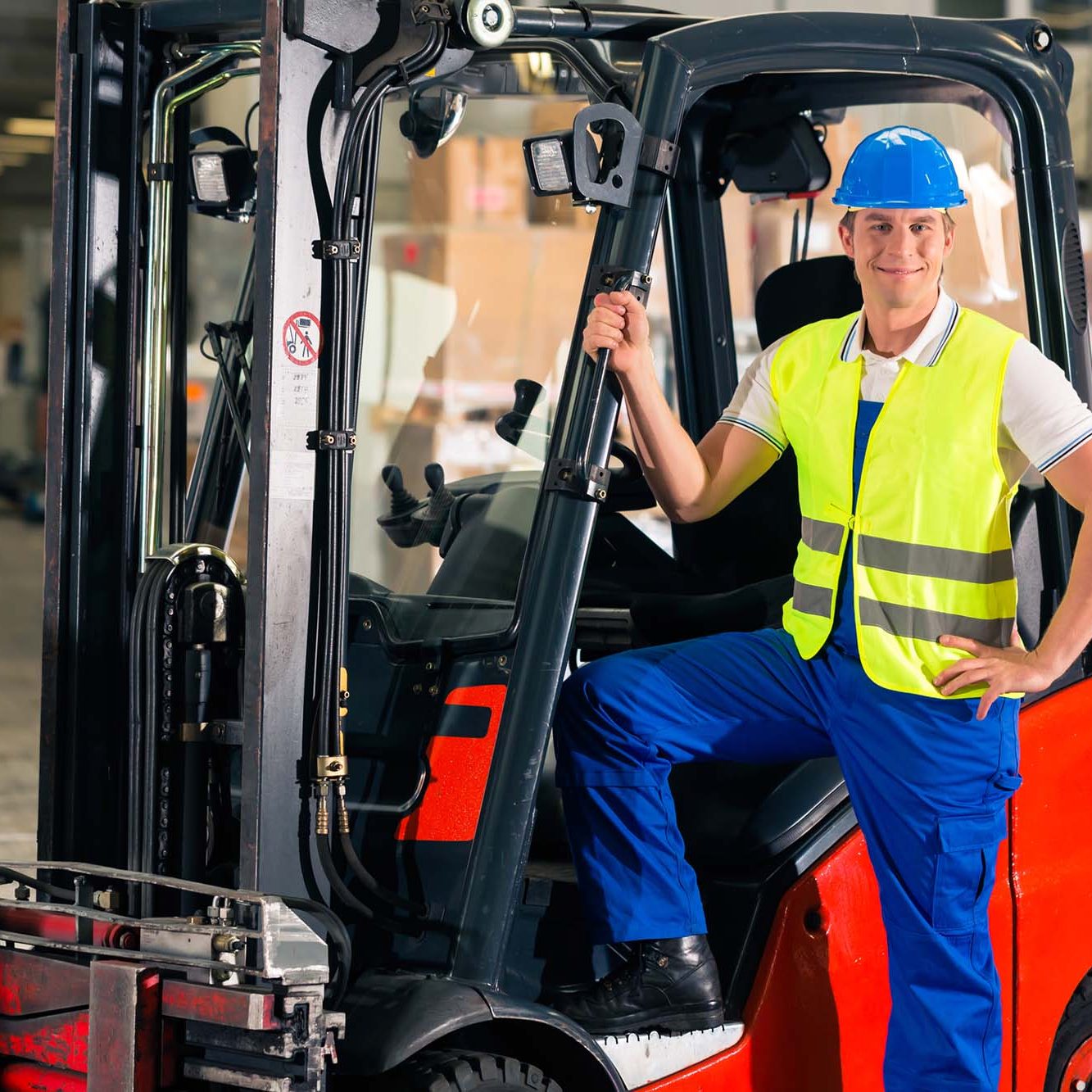 Man in high vis jacket standing on a red forklift