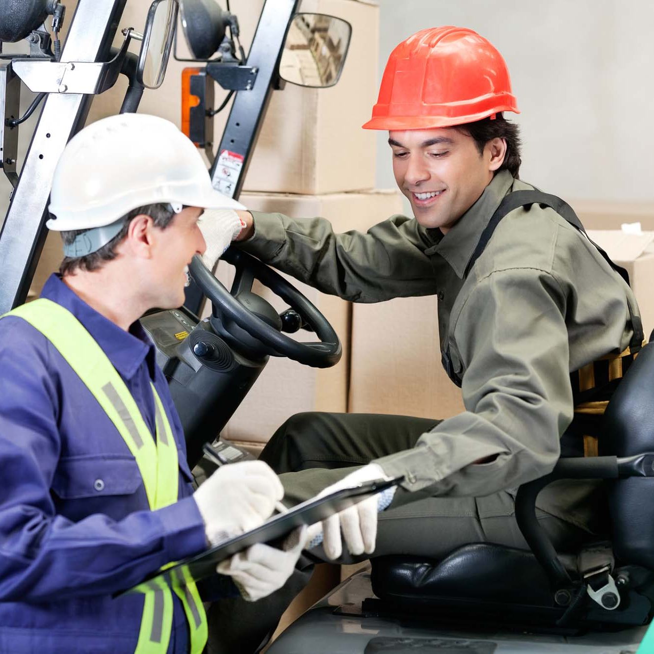 man using forklift getting assessed by his boss using clipboard